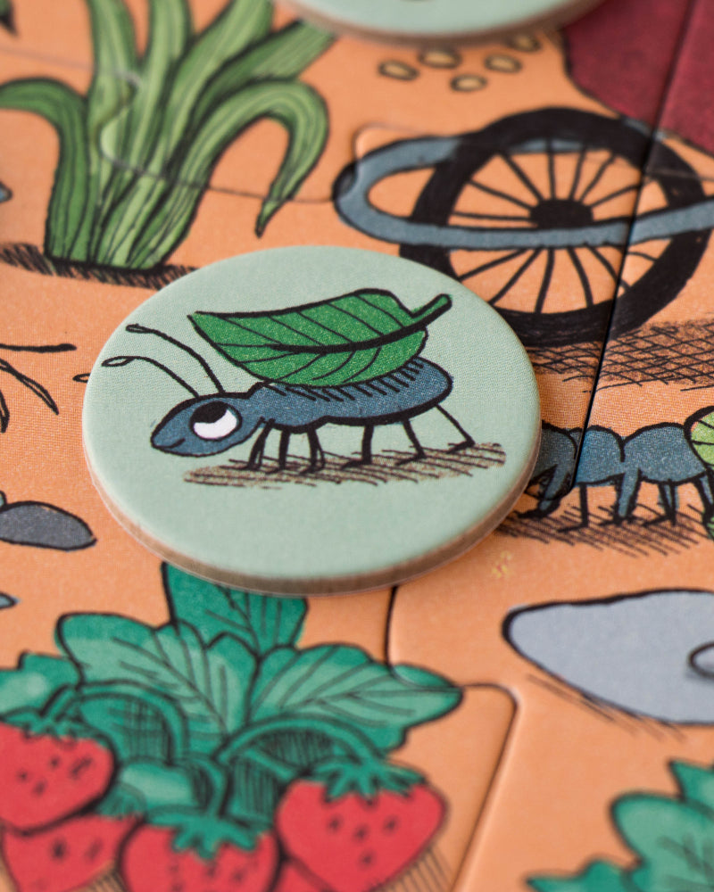 Close-up of a board game piece with a caterpillar design on a garden-themed board.
