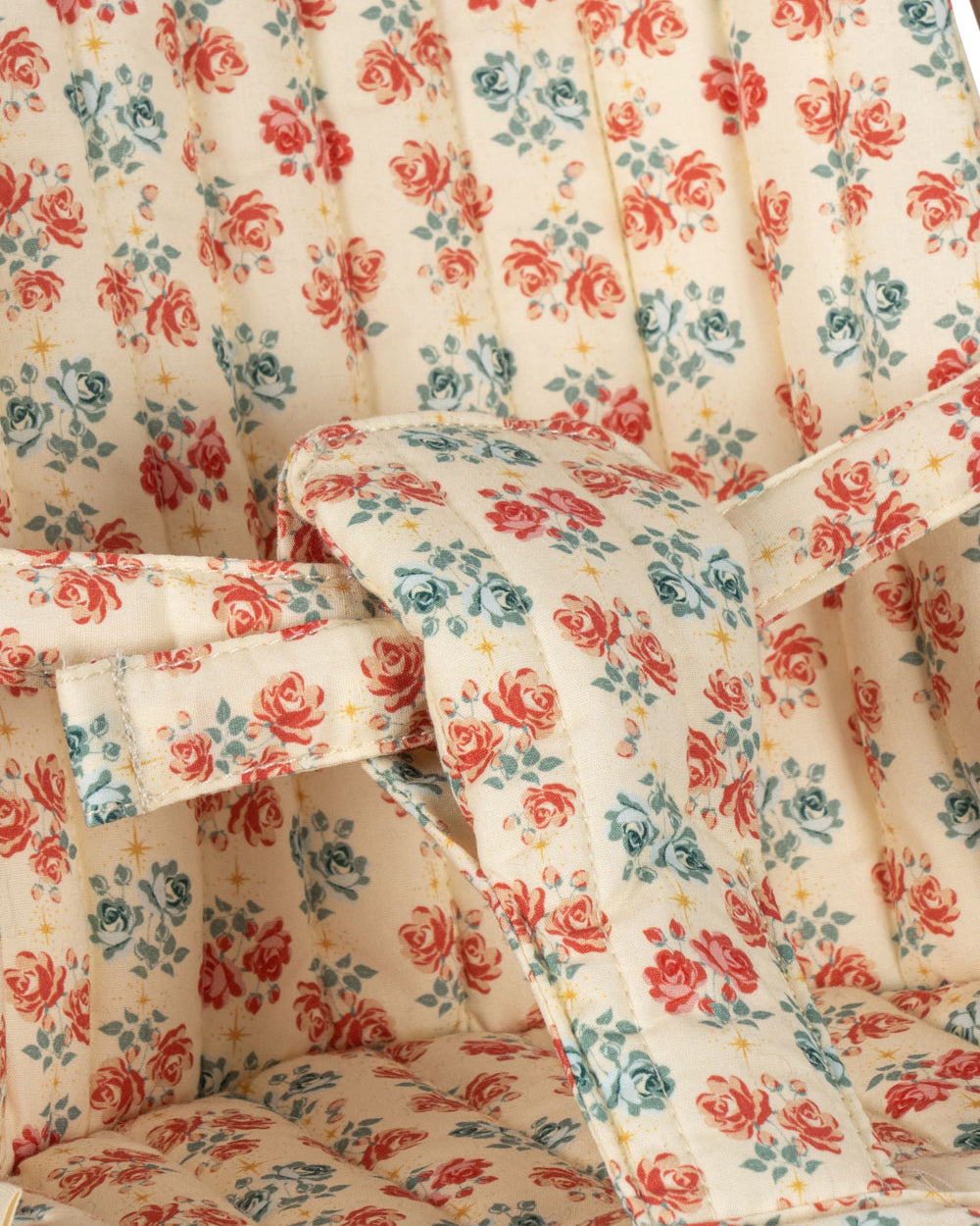 Close-up of coral and teal rose pattern fabric with safety harness on doll stroller seat