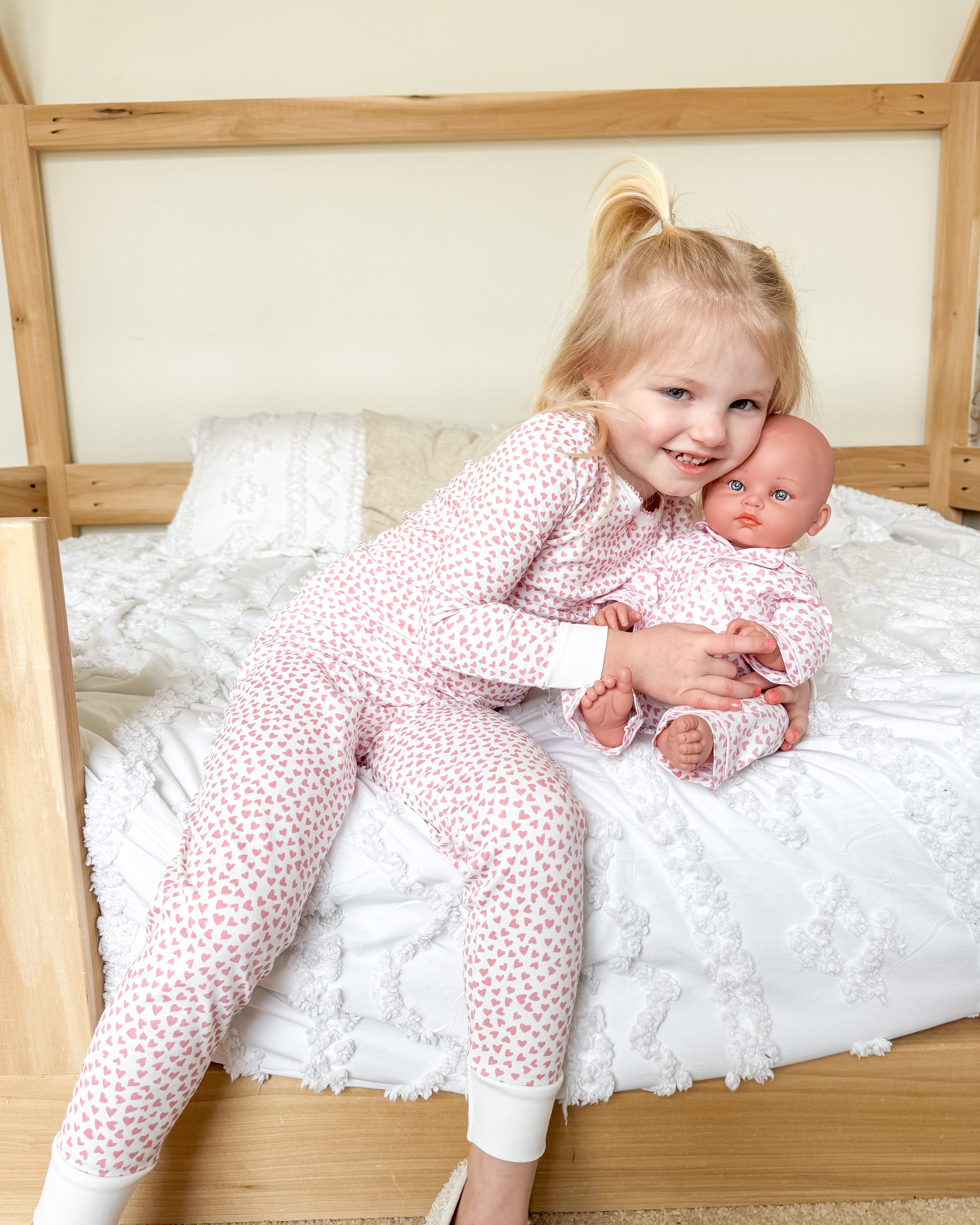 Girl hugging doll in pink pjs