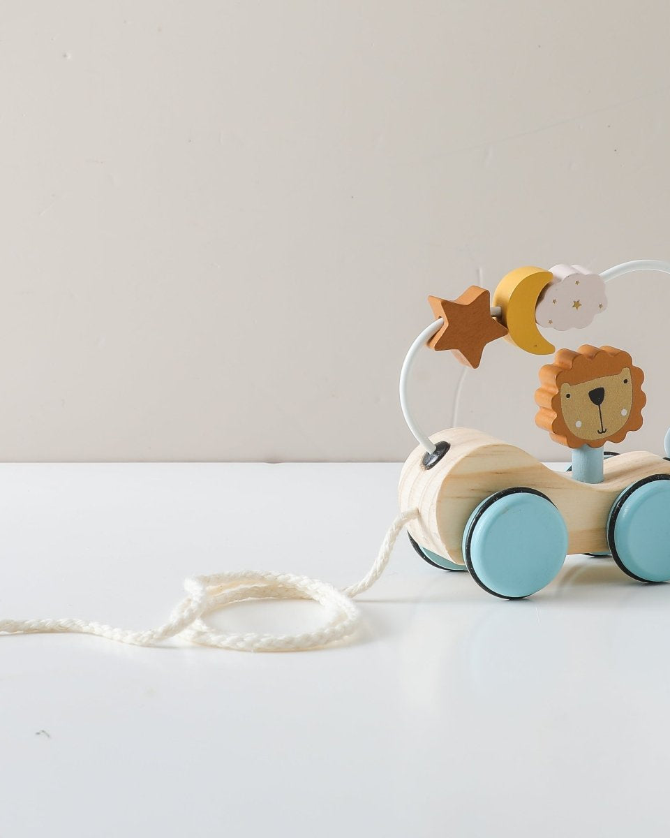 Wooden Montessori lion pull toy with natural finish and pastel blue wheels on hardwood floor