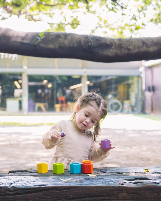 Child playing with colorful blocks on a wooden surface outdoors