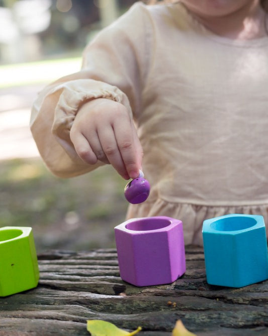 Child playing with colorful geometric shape sorting toys outdoors.