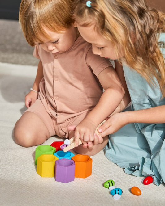 Two young girls playing with colorful building blocks on a light surface.