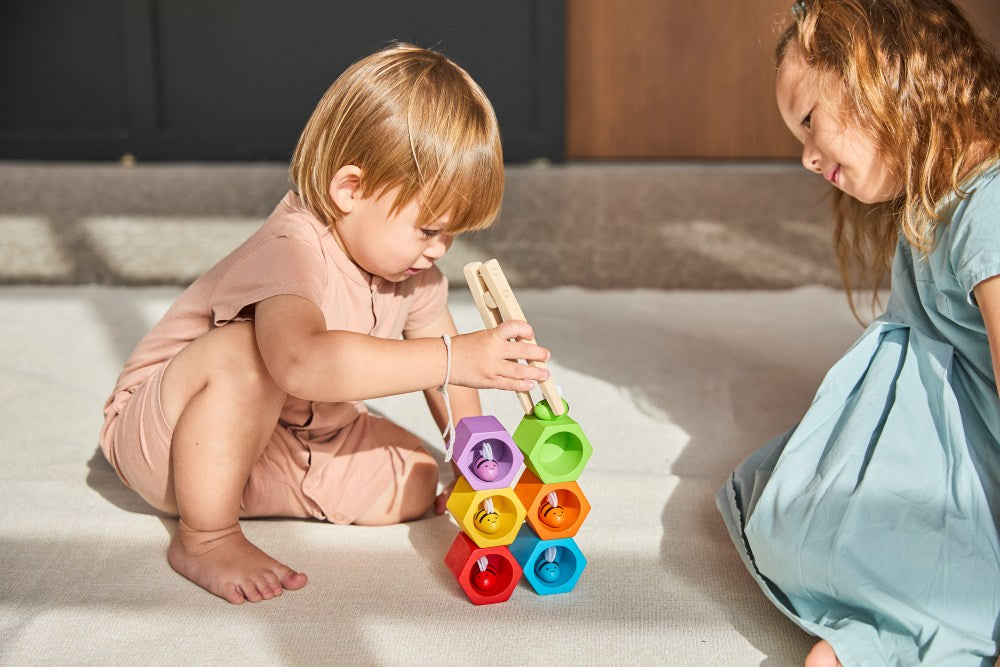 Two children playing with colorful building blocks on a bed.