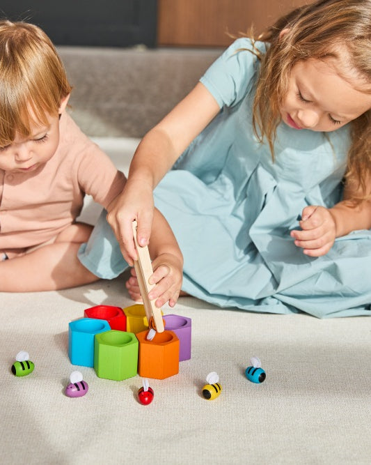 Two children playing with colorful toys on a light-colored surface.