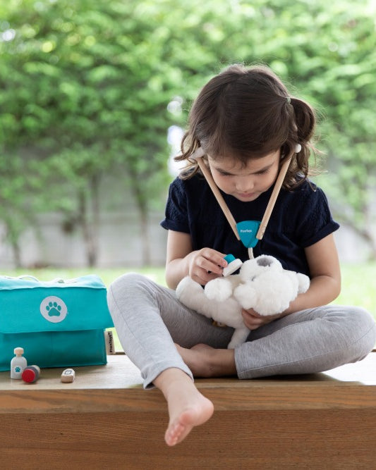 Child playing veterinarian with PlanToys wooden vet medical tools
