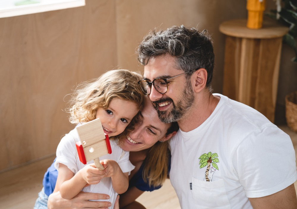 Man and woman holding a child, all smiling indoors.