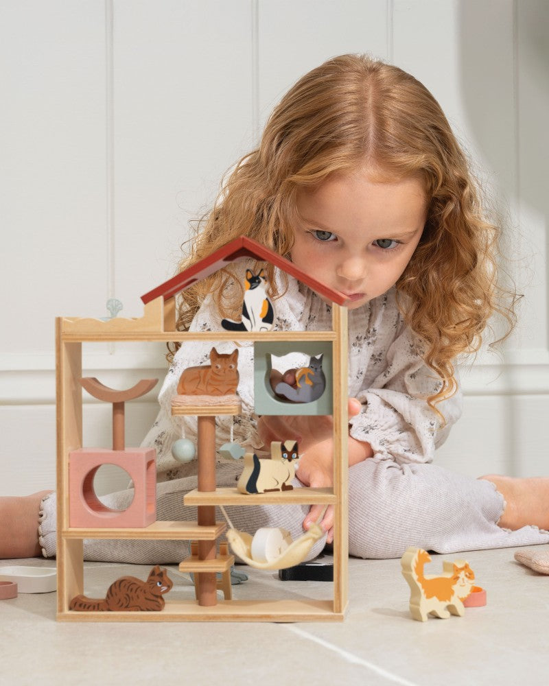 Child playing with a wooden animal playset on a light-colored floor.