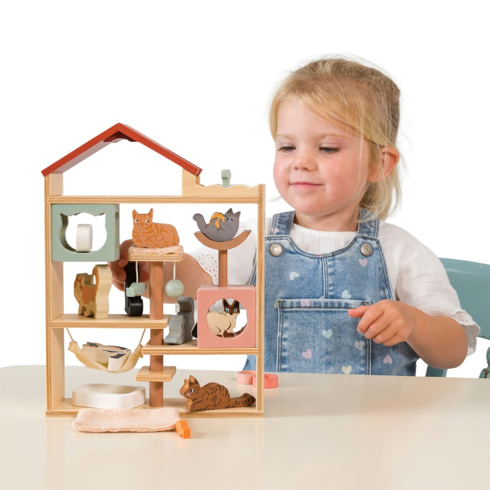 Child playing with a wooden toy house featuring animal figures on a white background