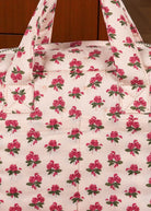 Close-up of Rosie Rose print fabric showing delicate pink roses with green leaves pattern and premium cotton texture
