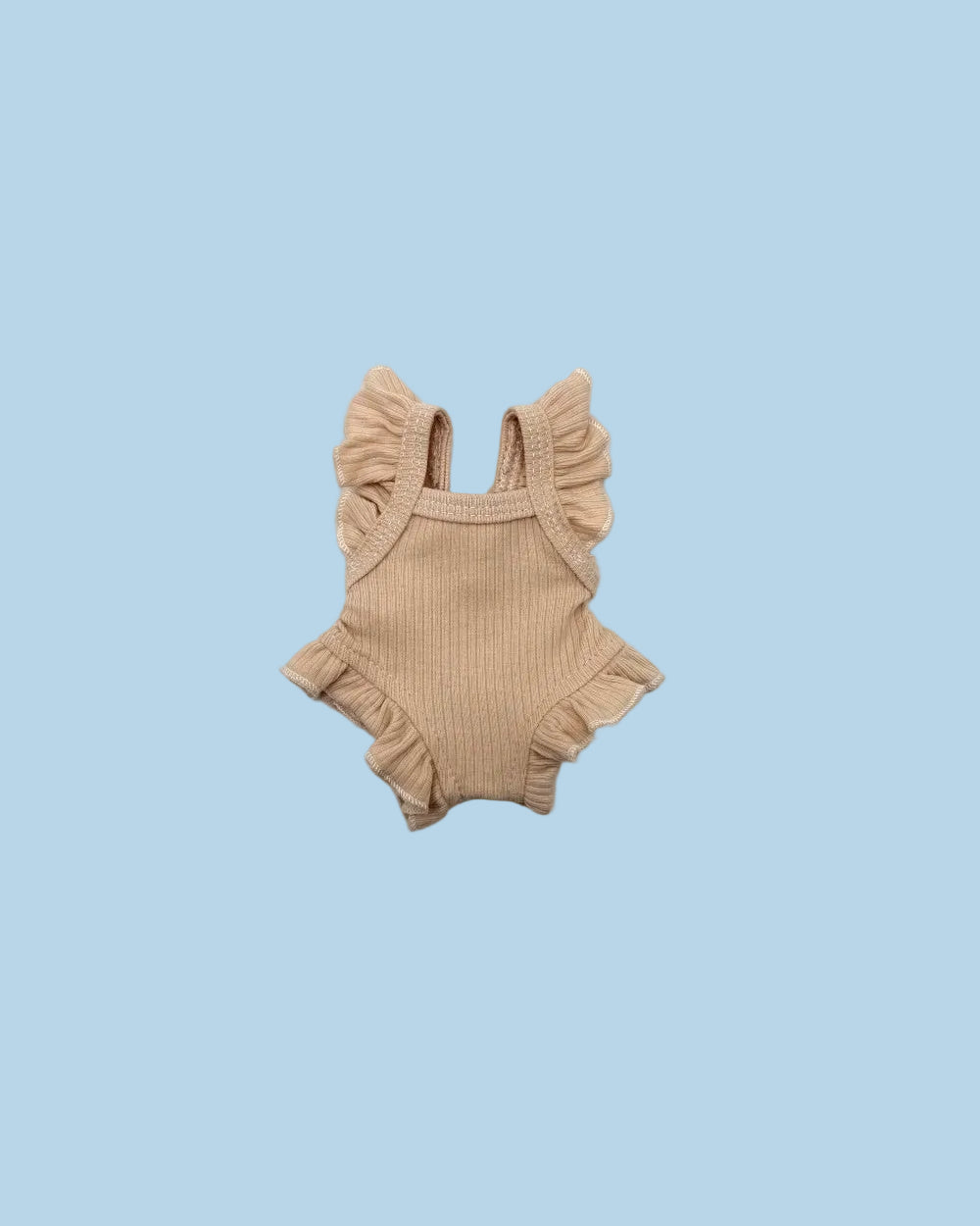 A small ribbed knit baby romper in a light tan or beige color, featuring ruffled shoulder straps and a ruffled hem, laid flat on a white background.