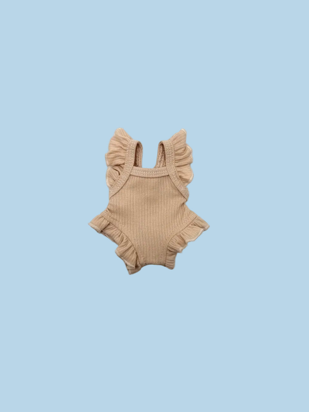 A small ribbed knit baby romper in a light tan or beige color, featuring ruffled shoulder straps and a ruffled hem, laid flat on a white background.