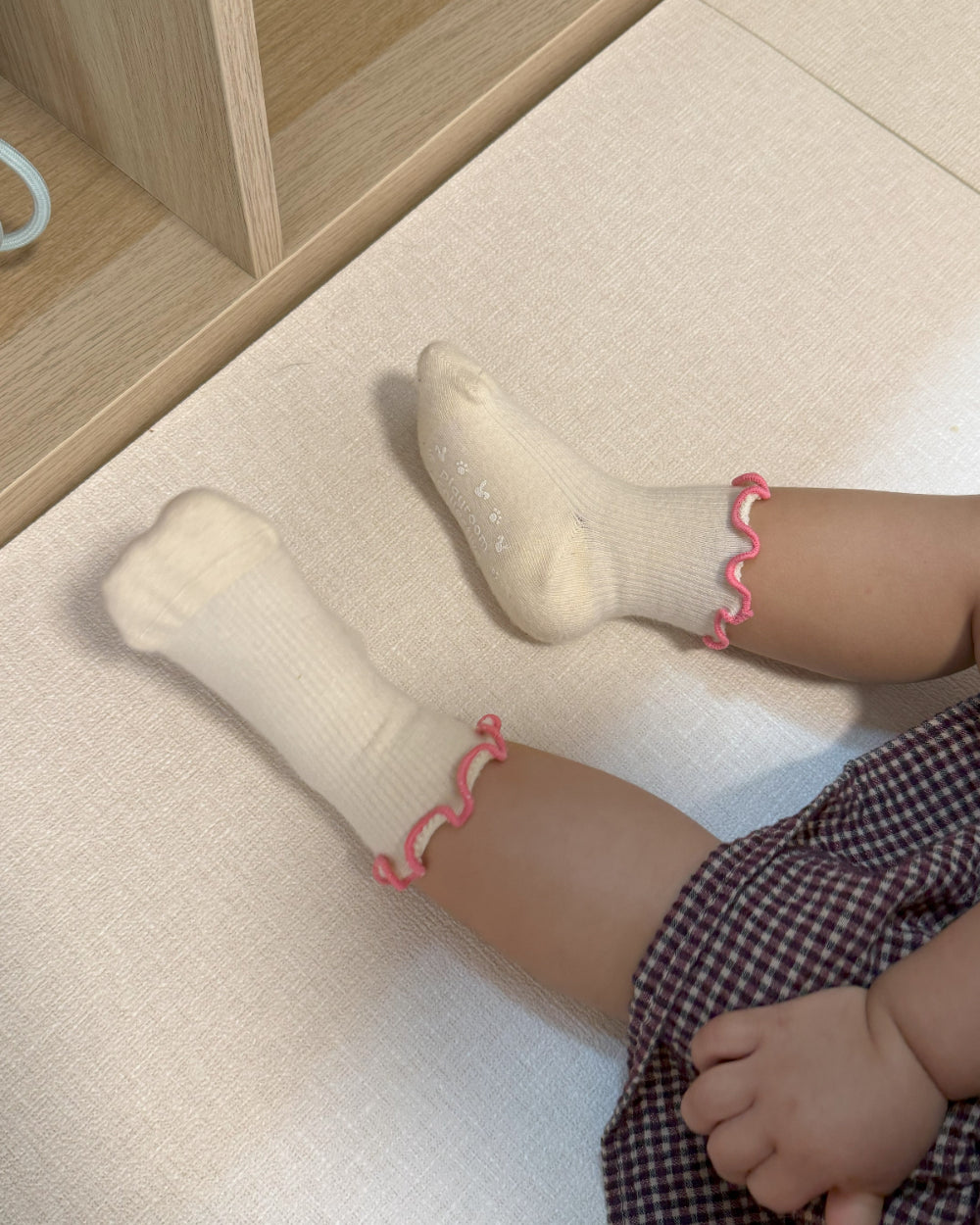 Child in cozy ruffle socks sitting cross-legged during indoor playtime