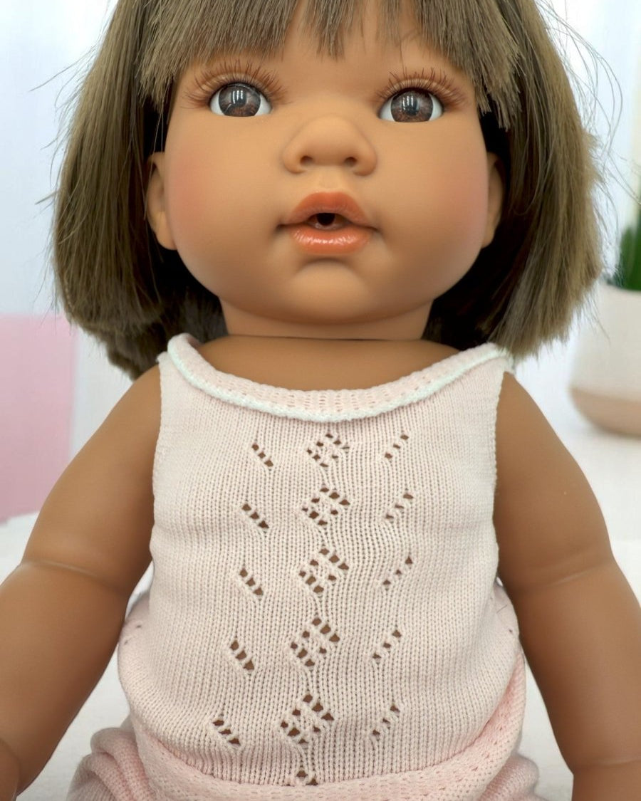 Lifelike baby doll Savannah celebrating diversity with straight brunette hair in pink pajama outfit