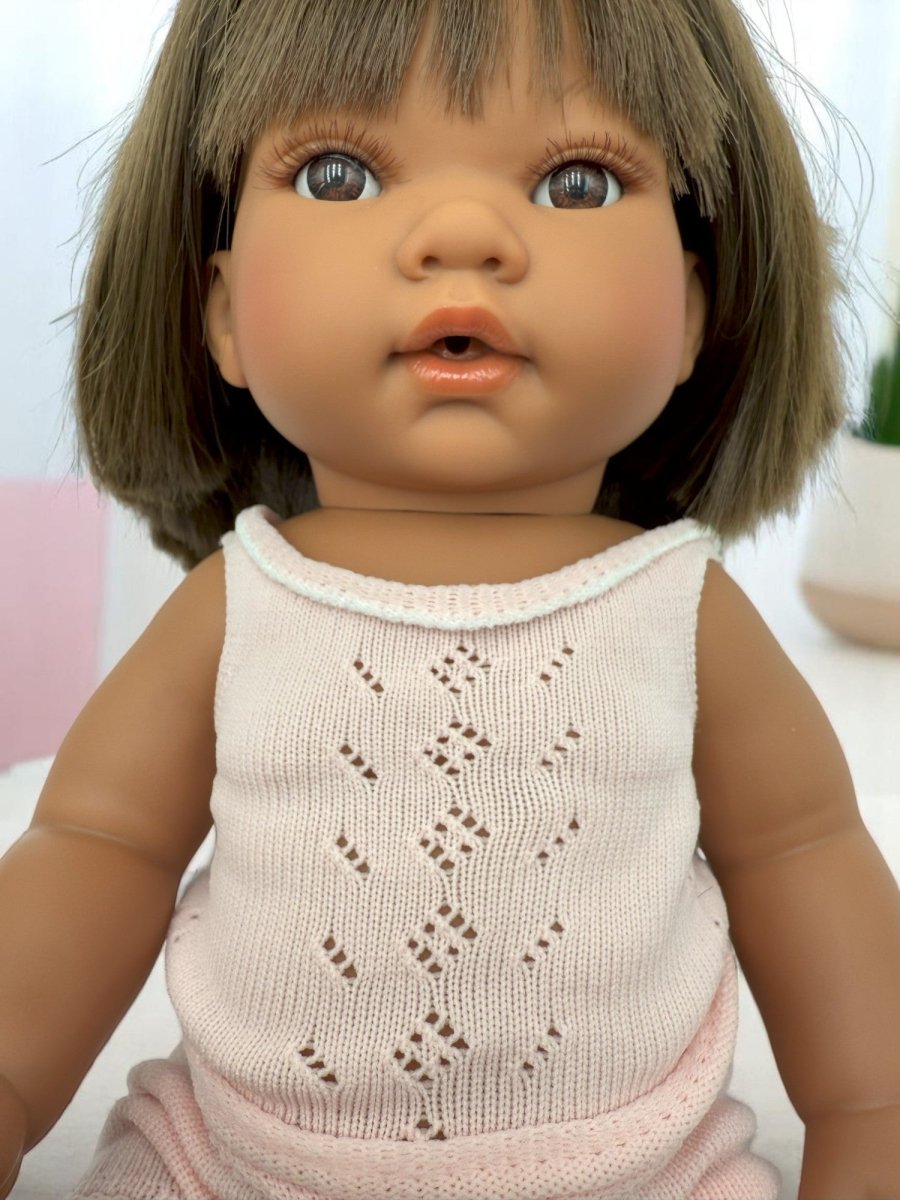 Lifelike baby doll Savannah celebrating diversity with straight brunette hair in pink pajama outfit