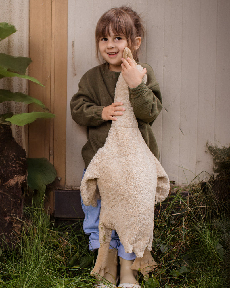Young children holding cream Senger goose companions outdoors during imaginative play