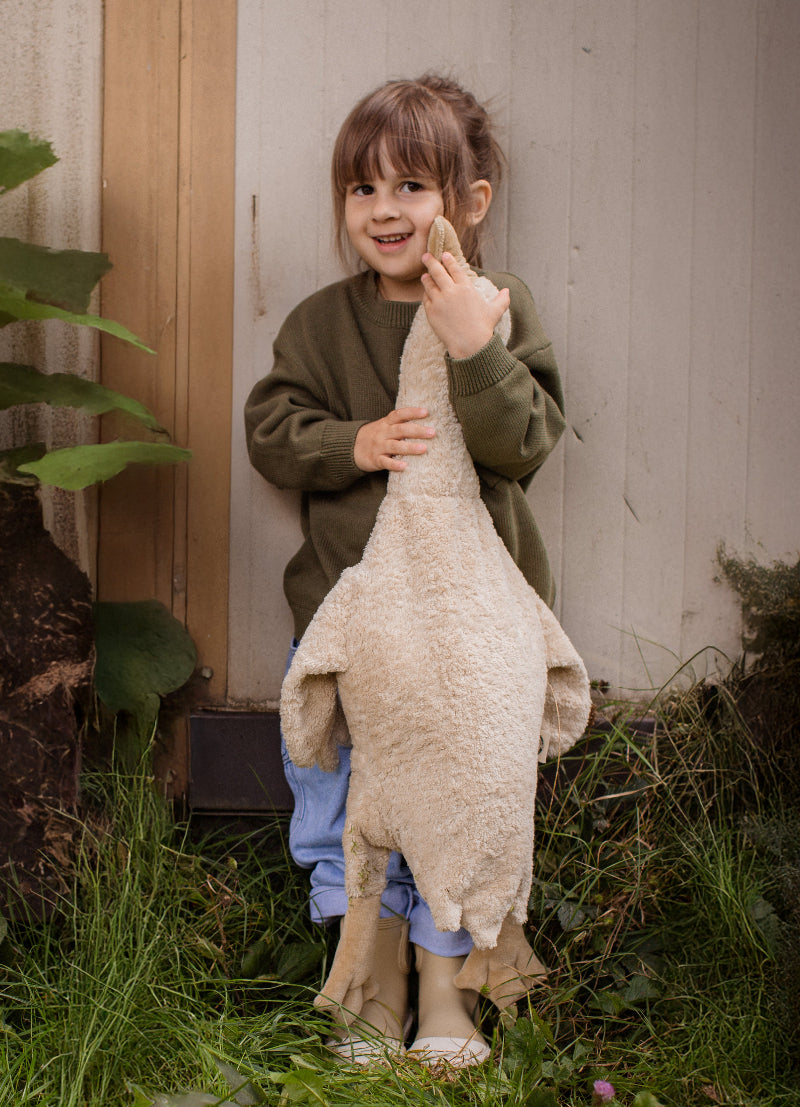 Young children holding cream Senger goose companions outdoors during imaginative play