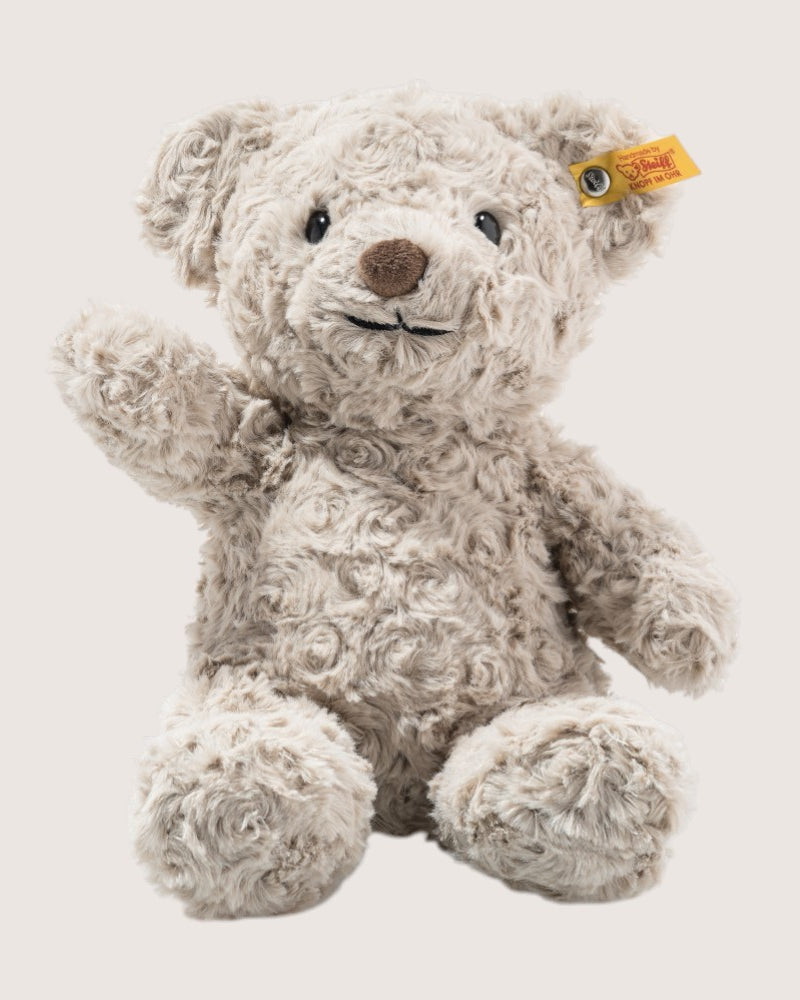 Plush teddy bear with a yellow tag on a light background