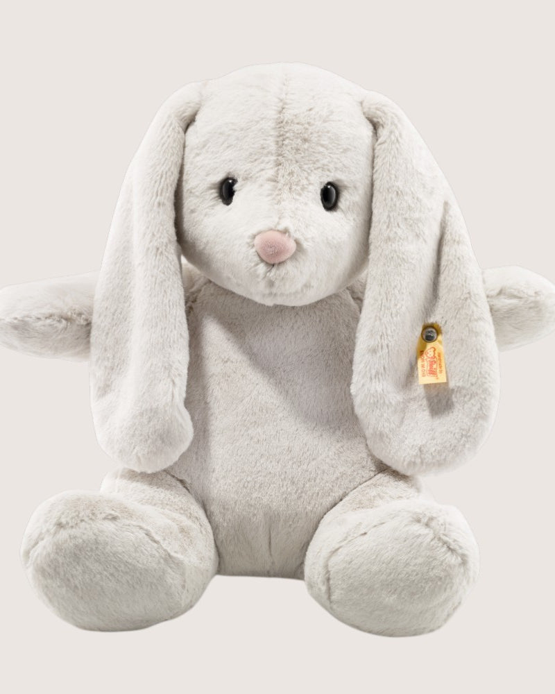 Plush toy rabbit with a visible brand tag on a light gray background