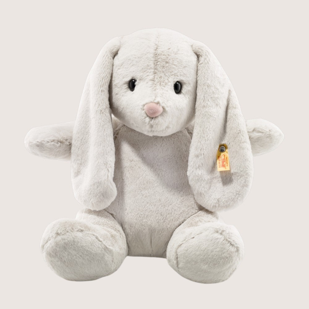 Plush toy rabbit with a visible brand tag on a light gray background