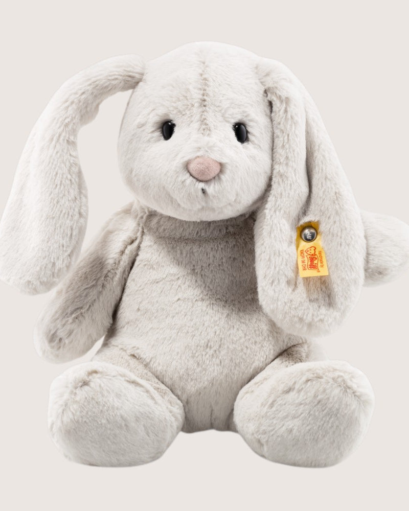 Plush bunny toy with a visible brand tag on a light gray background