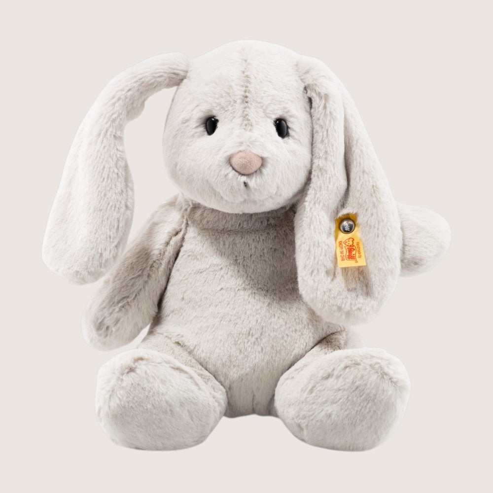 Plush bunny toy with a visible brand tag on a light gray background