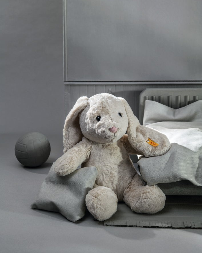 Plush bunny toy on a bed with a gray background