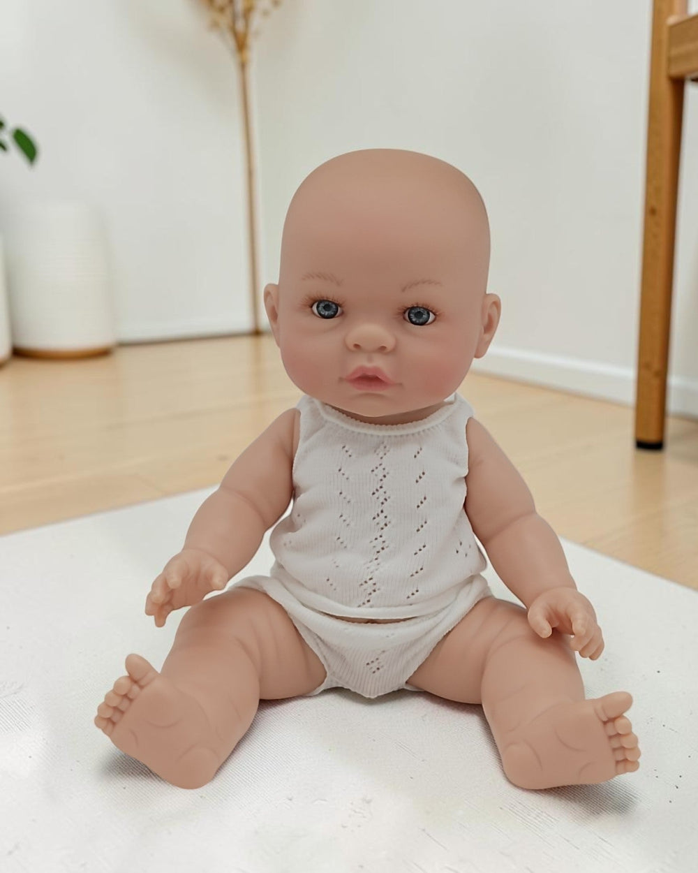 Baby doll wearing a white outfit on a light surface with a neutral background