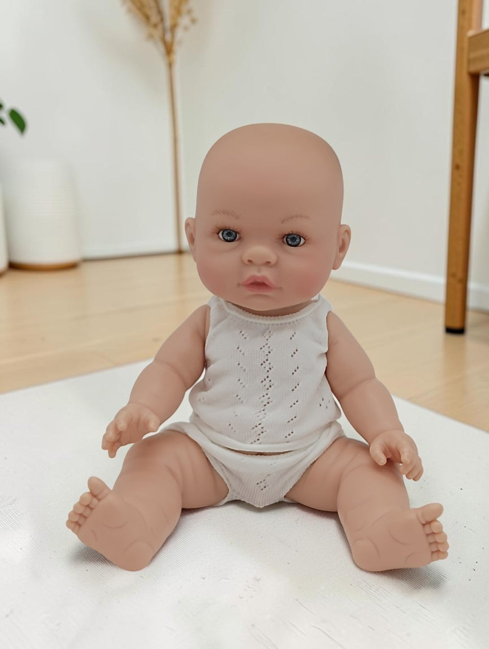 Baby doll wearing a white outfit on a light surface with a neutral background