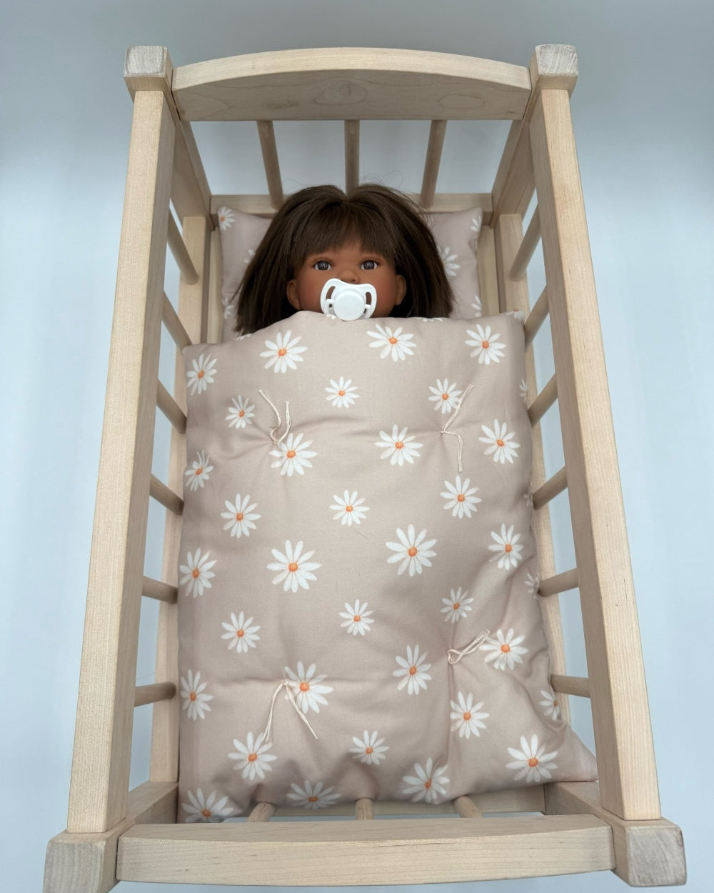 Taupe daisy doll bedding set with white flowers in wooden Bebenita doll cradle