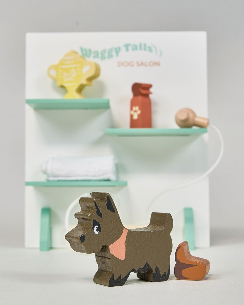 Wooden dog toy in front of a miniature dog salon set on a white background