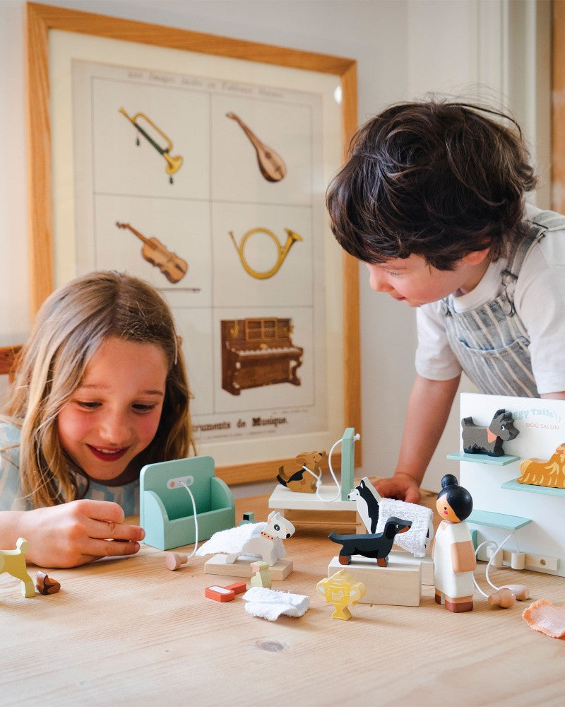Two children playing with toys at a table in a room with a poster on the wall.