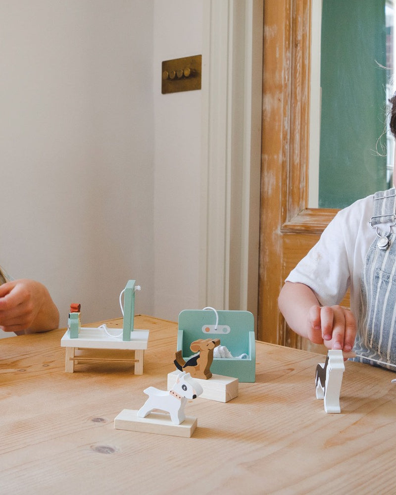 Two children playing with small figurines on a wooden table.