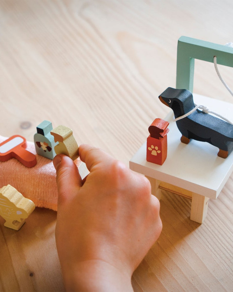 Hand interacting with wooden toys on a light wooden surface