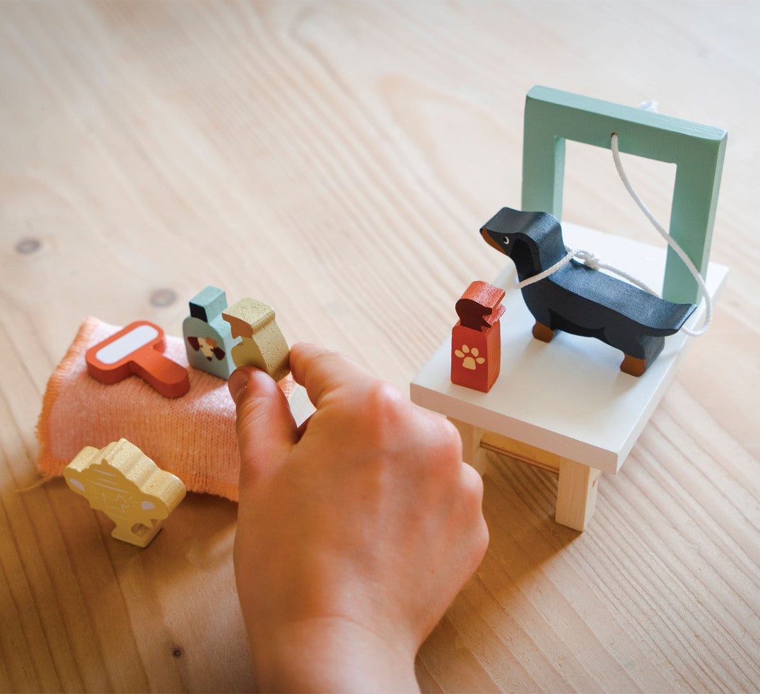 Hand interacting with wooden toys on a light wooden surface