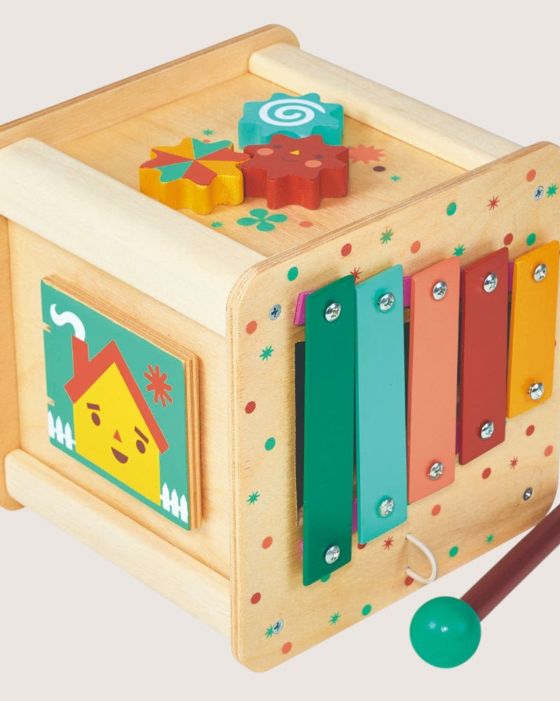 Wooden children's toy with colorful panels and a mallet on a light gray background