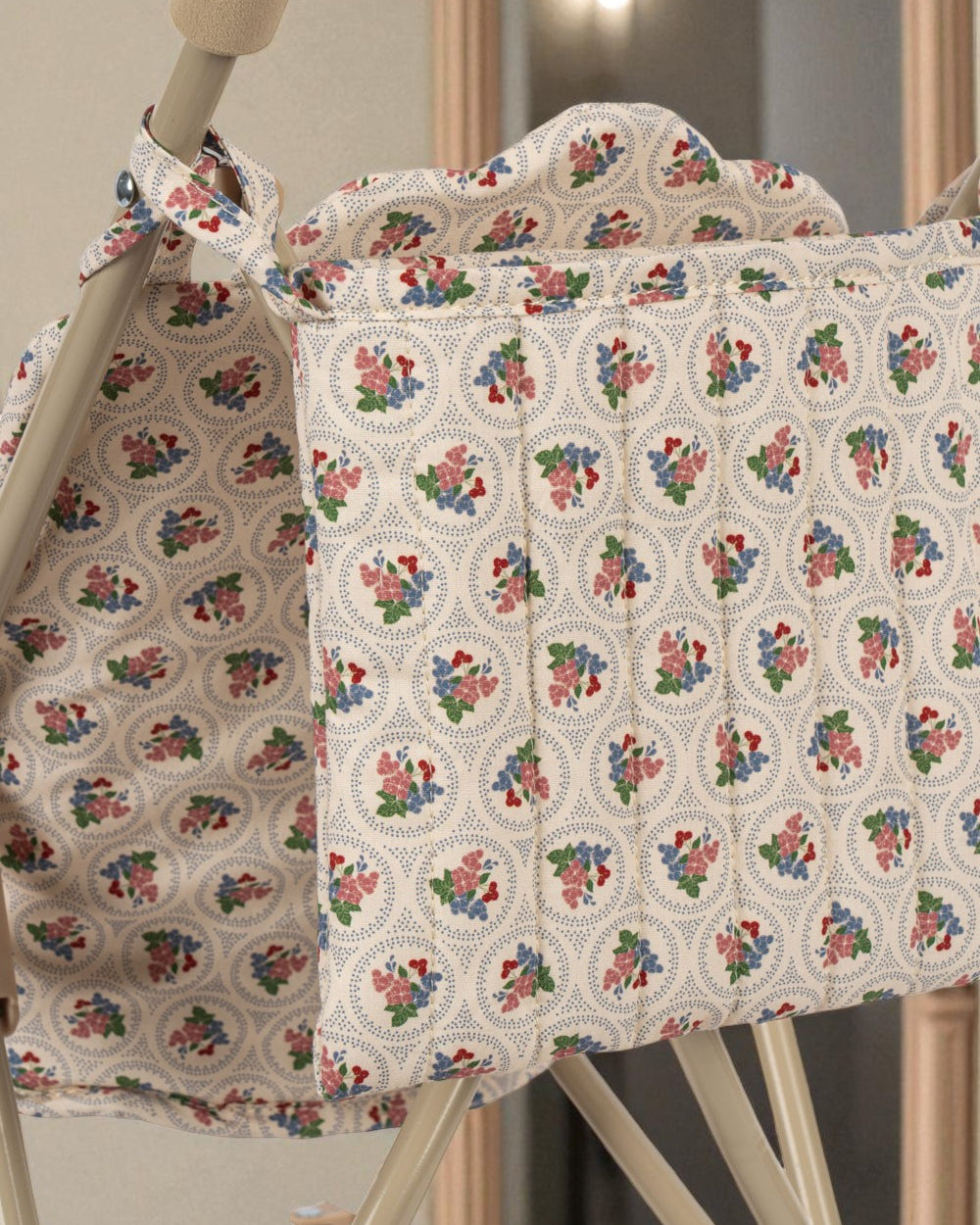 Romantic floral print detail showing coral and teal roses on padded doll stroller seat