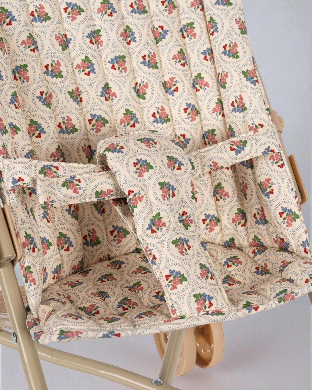 Close-up of vintage botanical print fabric with safety harness on collapsible doll pushchair
