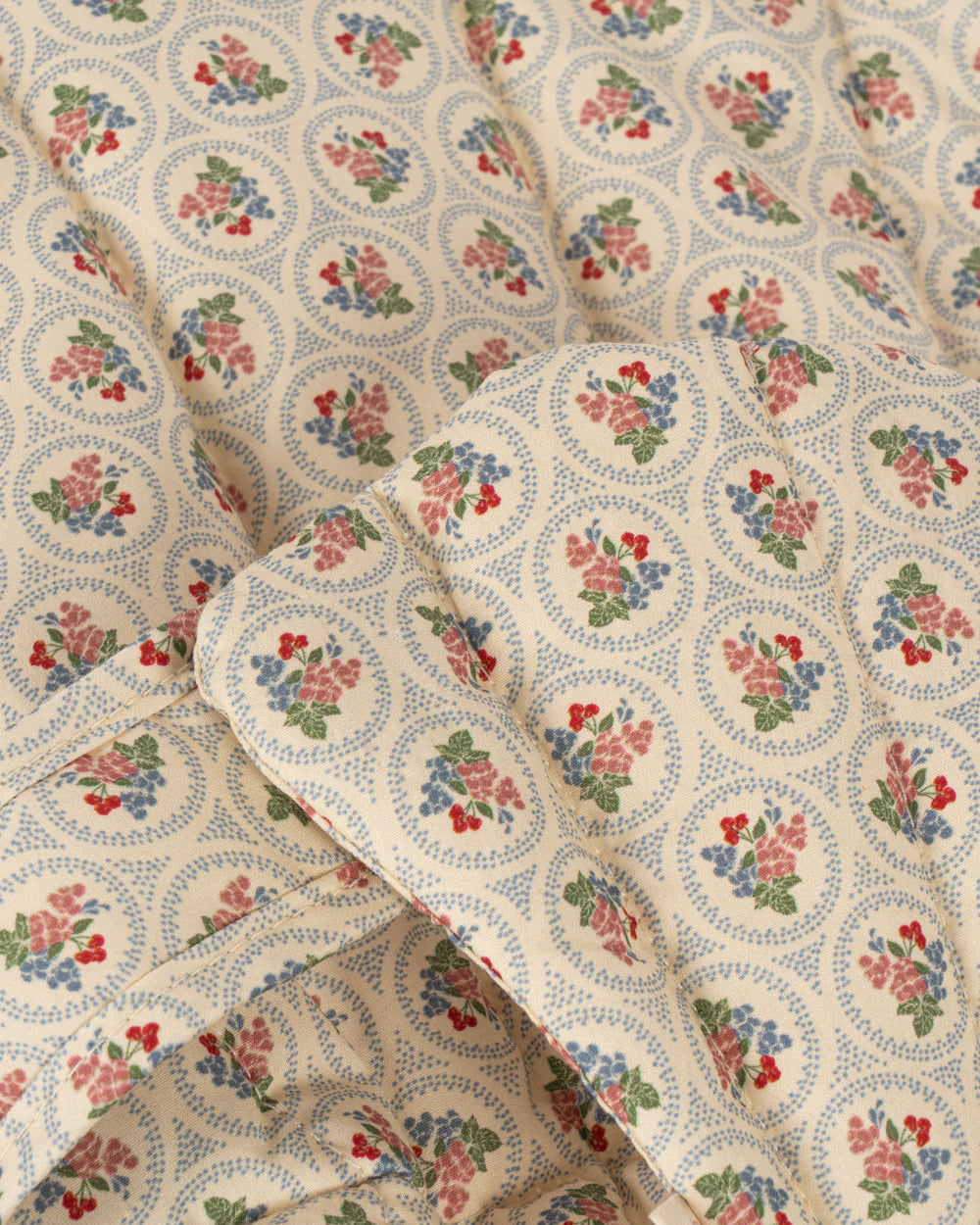 Close-up of Verona Blues print showing cornflower blue flowers with coral, cherry and green accents and dotted circle details