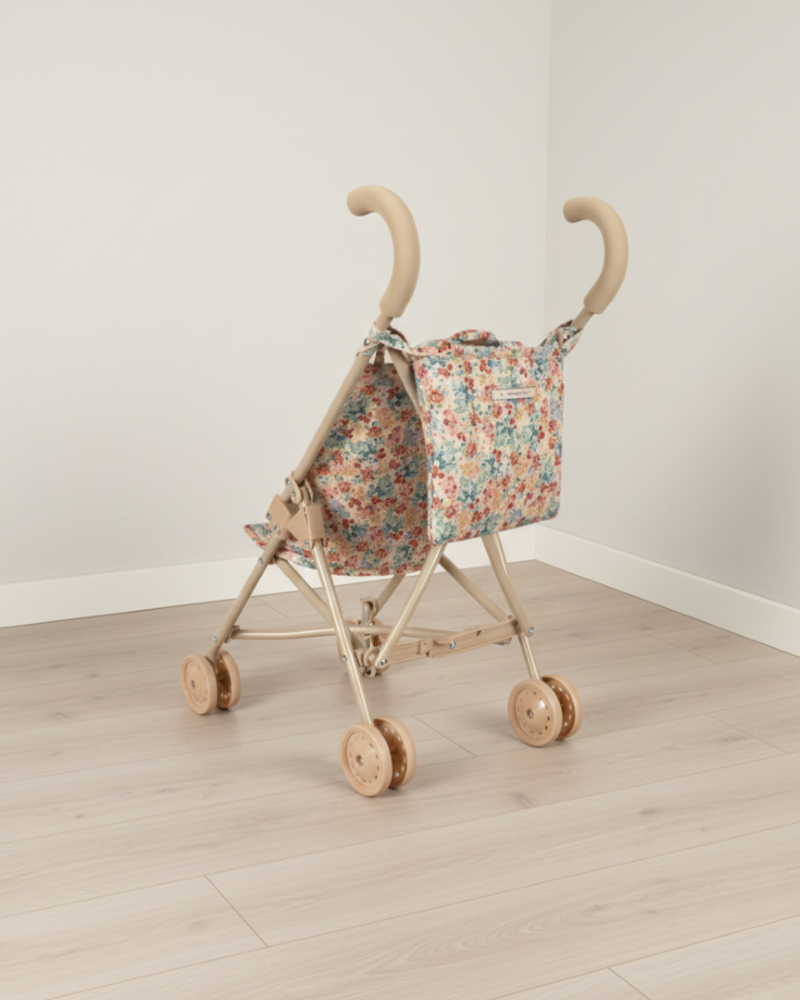 Floral-patterned baby buggy on a wooden floor with a white wall background