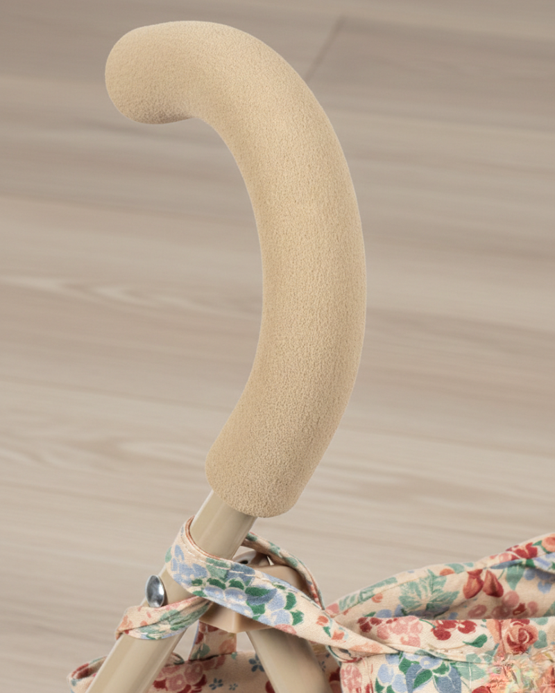 Beige stroller handle with floral fabric on a beige background