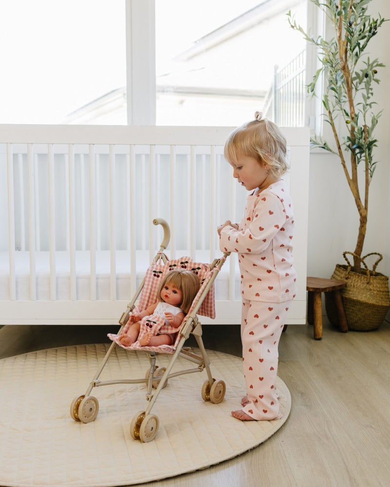 Child playing with a doll in a stroller in a nursery