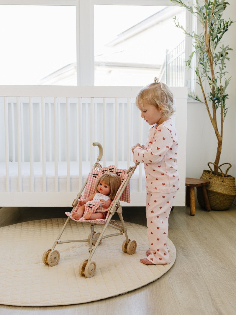 Child playing with a doll in a stroller in a nursery