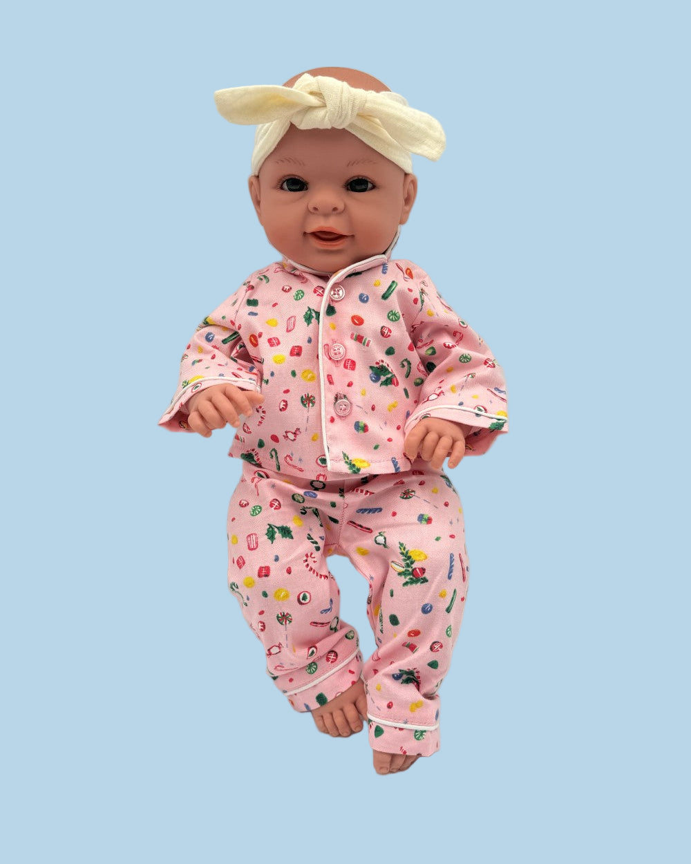 Coordinating doll and child pajama set in whimsical pink with colorful lollipop and candy pattern