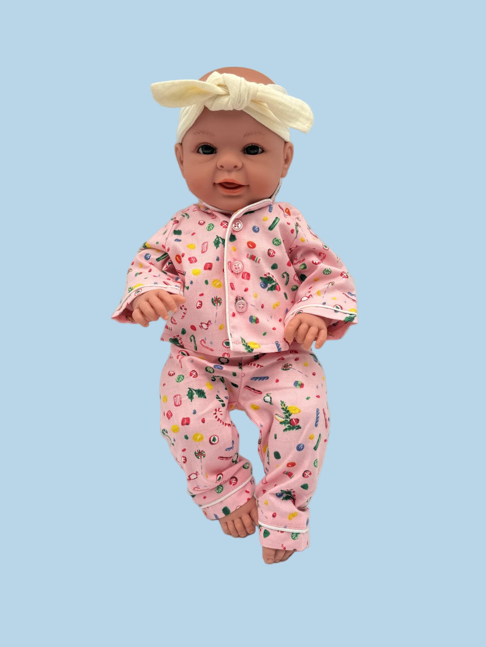 Coordinating doll and child pajama set in whimsical pink with colorful lollipop and candy pattern