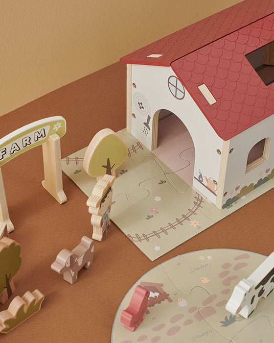 Close-up of barn interior with cow and chicken figures plus rolling truck carrying giraffe and horse in detachable trailer