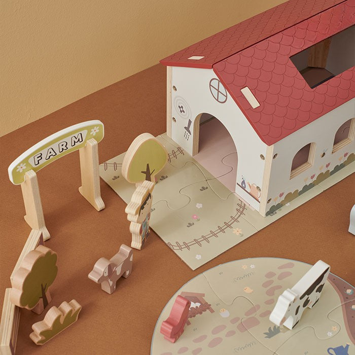 Close-up of barn interior with cow and chicken figures plus rolling truck carrying giraffe and horse in detachable trailer