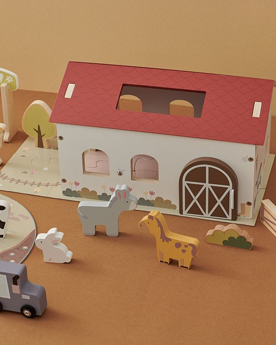 Overhead view of complete farm scene with fences arranged around barn, animals on puzzle mat, and trees placed as backdrop