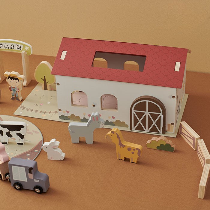 Overhead view of complete farm scene with fences arranged around barn, animals on puzzle mat, and trees placed as backdrop