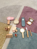 Set of wooden toy makeup items on a textured surface